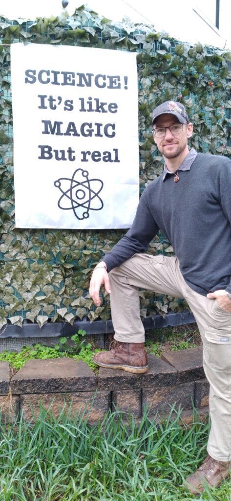 A man in brown boots and black shirt posing for the camera.